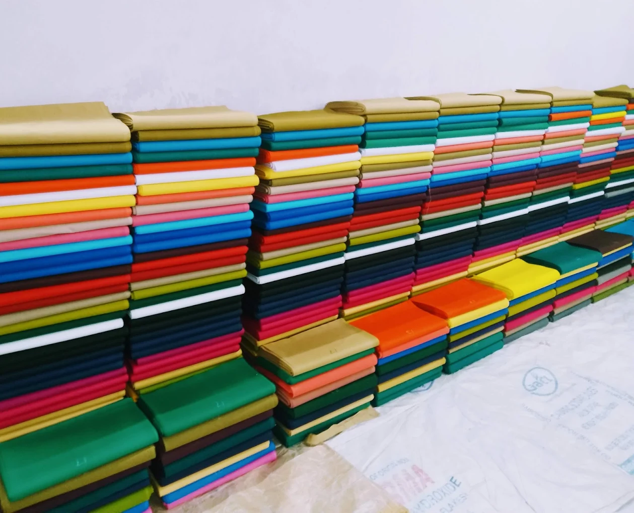 Stacked rolls of cotton astar lining fabric in multiple colours